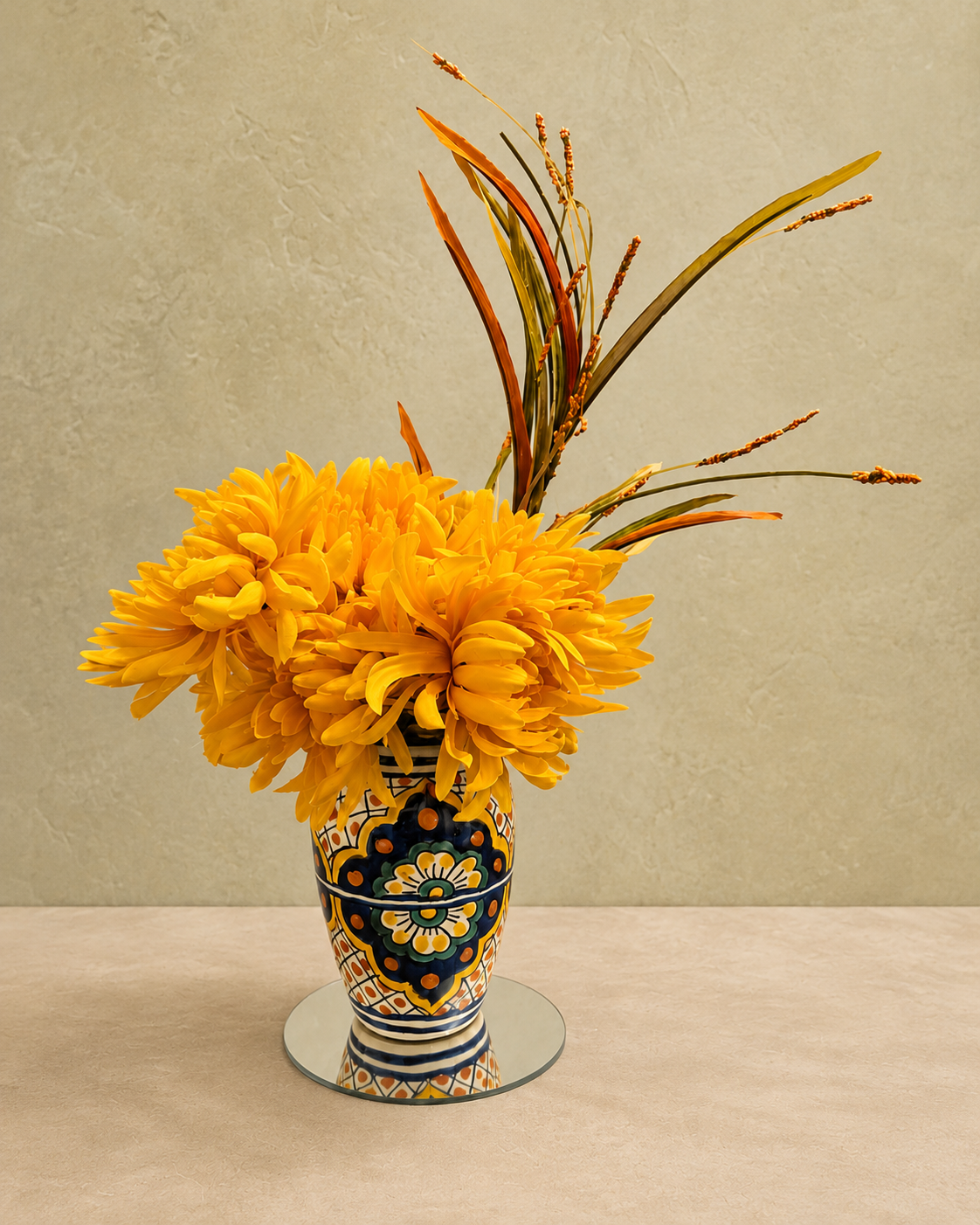 Yellow chrysanthemums and autumn leaves in a blue, cream and yellow vintage vase