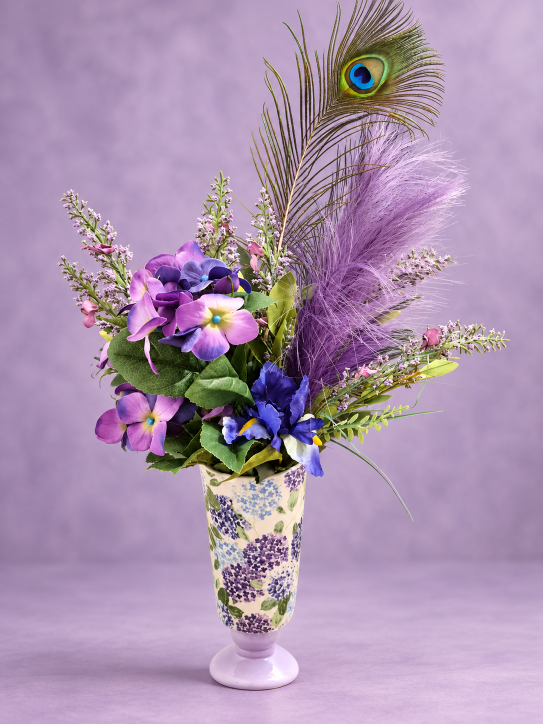 Purple flowers and a peacock feather in a tall purple and white floral vase
